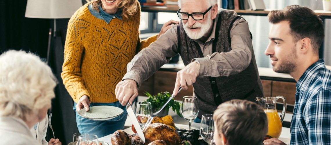 Grandfather,Cutting,Turkey,For,Family,On,Thanksgiving,Dinner
